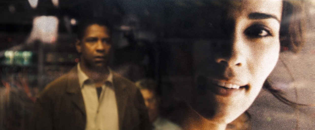 still from Deja Vu (2006) - an out of focus Denzel Washington stares at the projected image of Paula Patton on a futuristic display 
